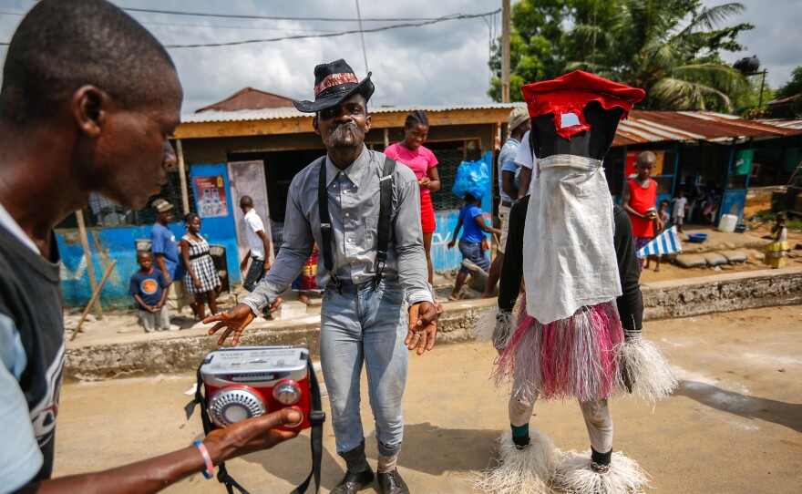 Liberian Santa, right, sings and dances in downtown Monrovia. Passers-by toss him coins so he'll have a happy and prosperous new year.