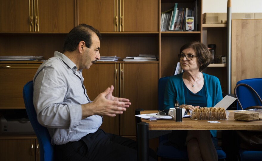 Bunni meets with Gerlinde Hollweg, a volunteer fundraiser. He coordinates with 30 Syrian lawyers across Europe who identify witnesses and collect refugee testimony about systematic abuse in Syria's prison network.