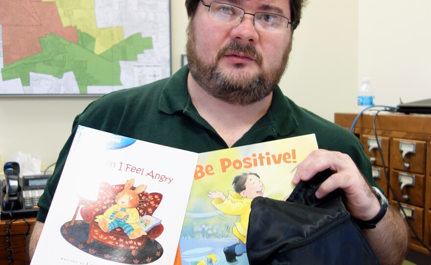 Scott Bonner, the Ferguson Public Library's director and its only full-time librarian, holds one of the "healing kits" that kids can check out.