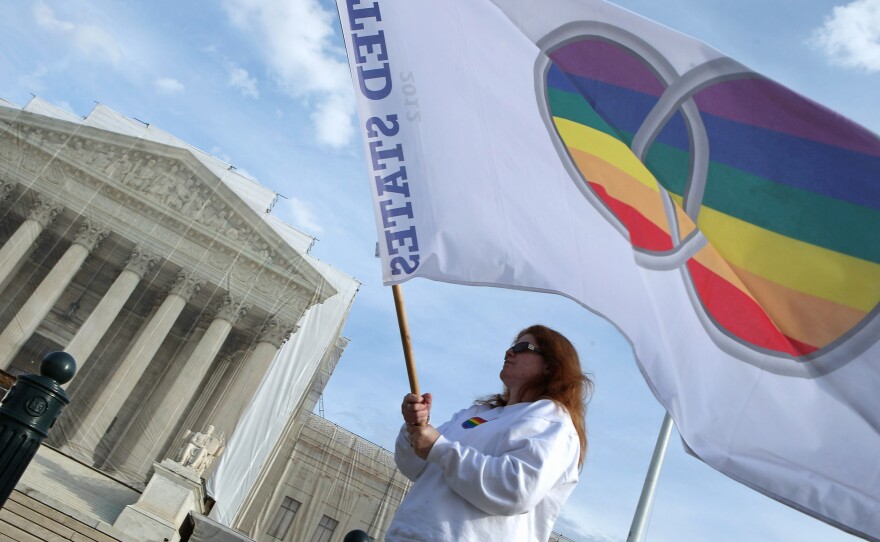 Kat McGuckin of Oaklyn, N.J., holds a gay pride flag while standing in front of the U.S. Supreme Court on Nov. 30.