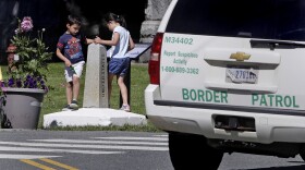 In this Wednesday, July 11, 2018 photo, two children, visiting the Haskell Library with their grandmother from Venezuela, play on the border pillar, as they circle back and forth between the United States and Canada under the watchful eye of a U.S. Border Patrol agent, seated in a vehicle, in Derby Line, Vt.