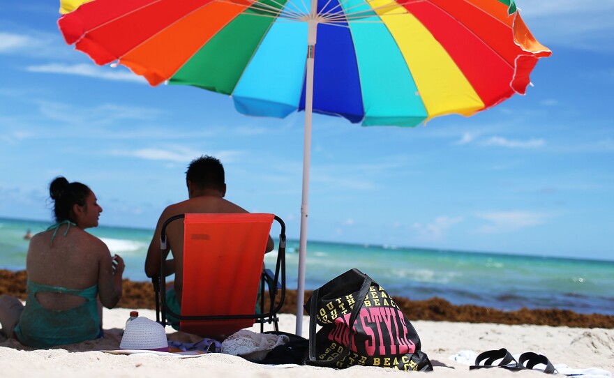 Tourists relax on Miami Beach last August. Travel experts had been predicting that this summer would bring out our desire to take vacations and have fun. The latest jobs report confirms it: Employers are hiring to help you enjoy the season.