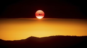 A plane battling the Ferguson Fire passes the setting sun in unincorporated Mariposa County Calif., near Yosemite National Park on Sunday, July 15, 2018.
