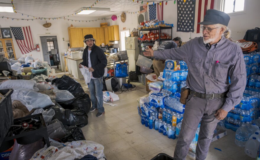 Sam Schultz points out the piles of clothes, food and water that will be donated to migrants in Jacumba Hot Springs, Nov. 15, 2023.