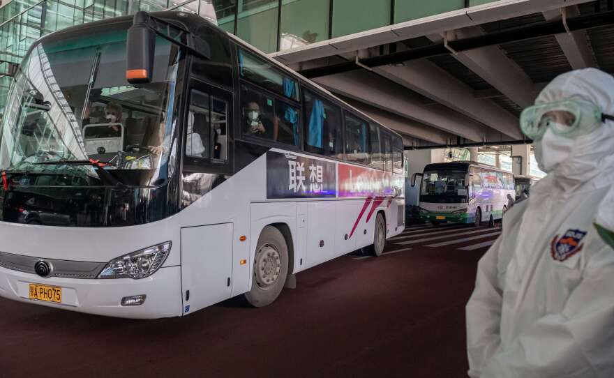 A bus carrying members of the World Health Organization team investigating the origins of the COVID-19 pandemic leaves Wuhan's airport following their arrival at a cordoned-off section in the international arrivals area on Thursday.