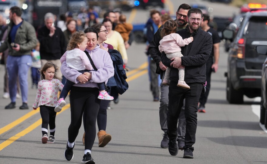 Law enforcement officers escort families with children away from the Temple Israel synagogue on March 12, 2026, after a shooting and vehicle ramming attack by a person inspired by Hezbollah.