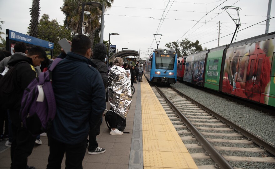 Migrants and asylum seekers wait for the trolley at Iris Avenue in San Ysidro, April 19, 2024. . More than 90% of them have plans to connect with family and friends in other parts of the country.