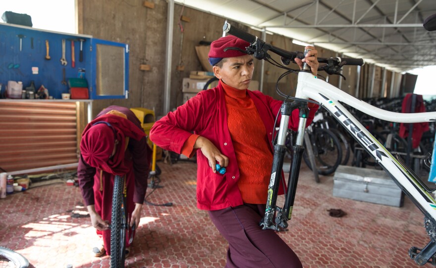Jigme Kunga Lhamo repairs a bicycle. She is one of the main mechanics on the 2,500-mile bicycle trip the nuns take to educate villagers about the dangers of trafficking.