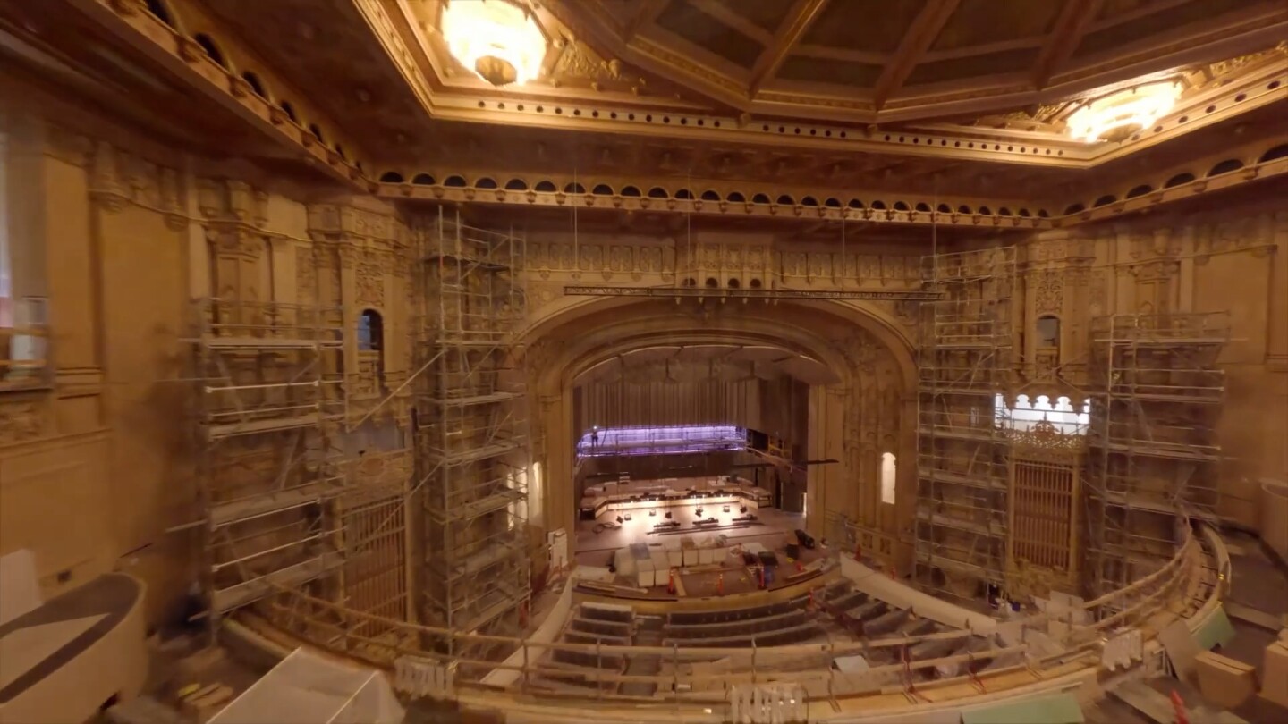 The interior of Symphony Hall is shown looking down at the stage from the balcony. Scaffolding can be seen on either side of the stage in this undated photo.
