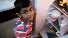 Daliya Ali's oldest son looks up from peeking into the refrigerator in his family's two-bedroom El Cajon apartment, July 25, 2017. 