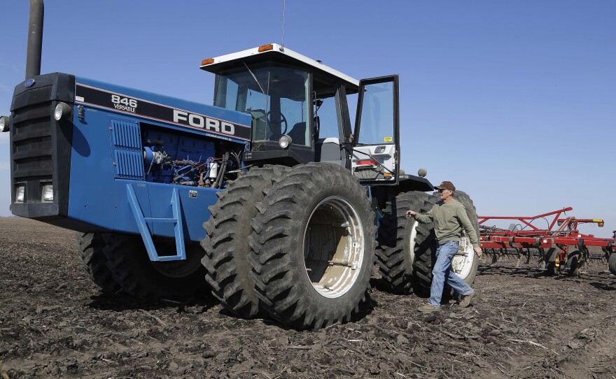 An Illinois corn and soybean farmer walks to his tractor while cultivating his field.