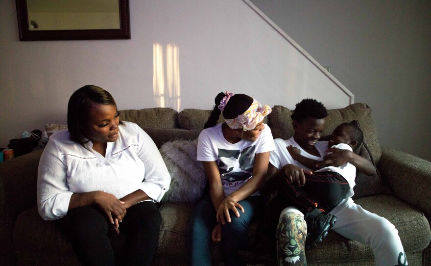 Maryanne Lundy, left, and her children, Malaysia Hill, Meliq Hill and Cornelius Madison sit on their couch in their home on Friday, Nov. 19, 2021 in Indianapolis.