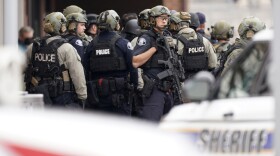 Police stand outside a King Soopers grocery store where a shooting took place Monday, March 22, 2021, in Boulder, Colo.