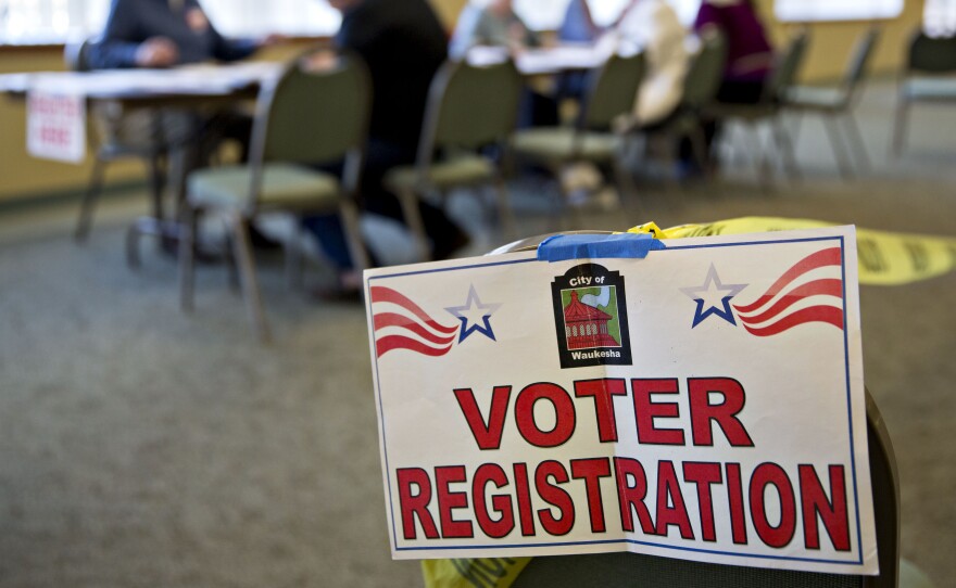 A voter registration sign hangs near a table where residents fill out paperwork at a polling location during the presidential primary vote in Waukesha, Wis., on April 5.