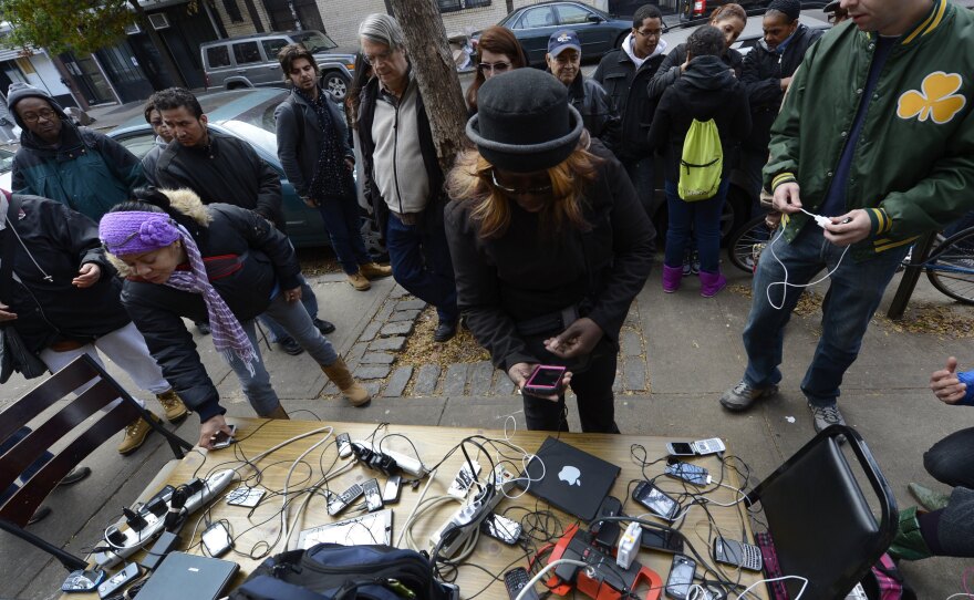 People wait to charge cellphones and laptops Thursday at a generator set up in the West Village. Superstorm Sandy left large parts of New York City without power.