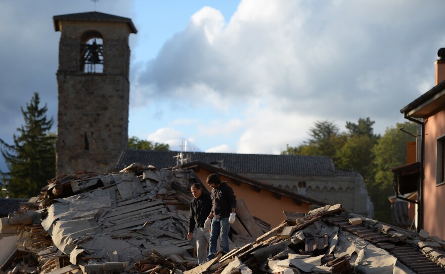Two men walk on a damaged home after a strong earthquake hit Amatrice, Italy, on Wednesday.