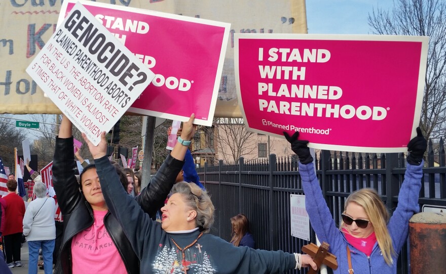 Planned Parenthood supporters and an opponent of the organization try to block each other's signs during a protest and counterprotest Saturday in St. Louis.