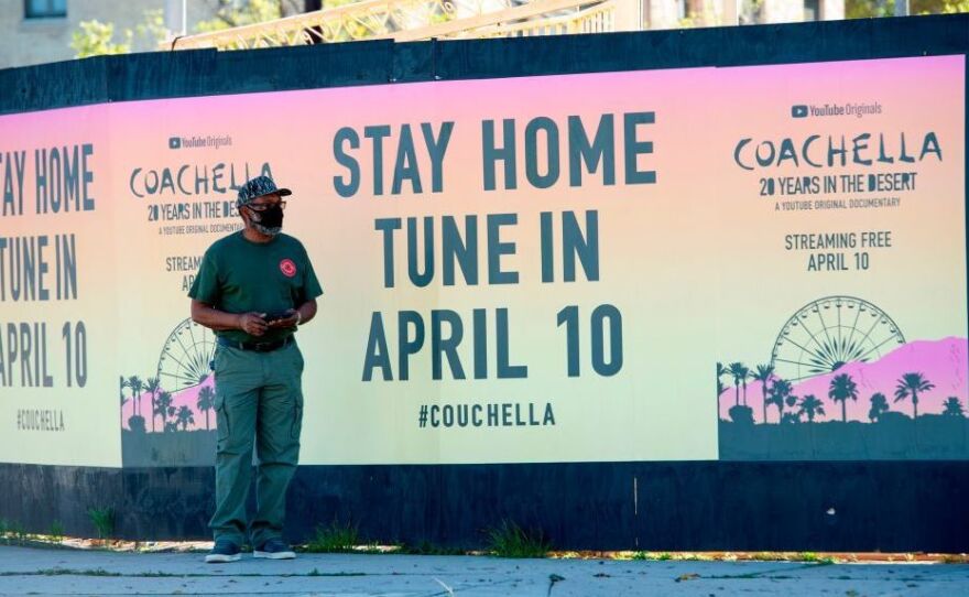 A man stands in front a poster advertising an "at home" streamed Coachella event in April in Hollywood, Calif.