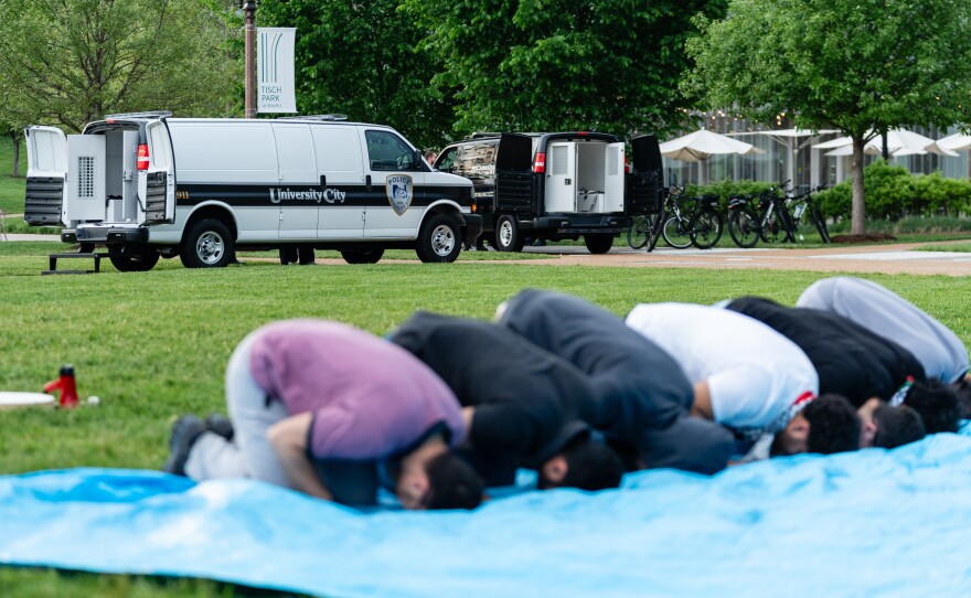 Prisoner vans are readied as Muslims pray during a pro-Palestine rally on April 27 at Washington University.