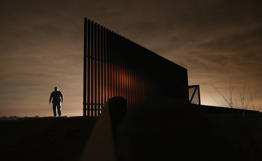 Border Patrol agent Sal De Leon stands near a section of the U.S.-Mexico border fence while on patrol last year in La Joya, Texas.