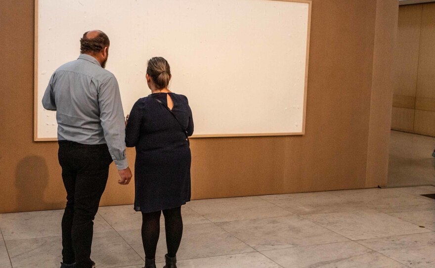 Visitors view a blank canvas that is part of "Take the Money and Run," by Jens Haaning, at the Kunsten Museum of Modern Art in Aalborg, Denmark. The piece is part of an exhibition called <em><a href="https://kunsten.dk/da/udstilling/work-it-out-11796">Work It Out</a></em>, which explores people's relationship with work.