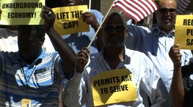 San Diego taxi drivers hold signs and wave American flags at a press conference on Thursday, August 28, 2014 announcing a proposed lift on the number of taxicab permits.