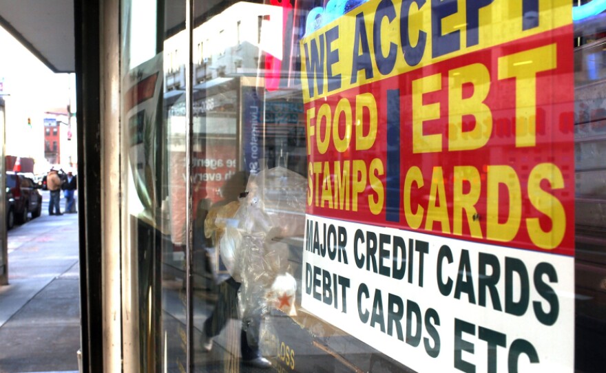 A sign in a New York City market window advertises the acceptance of food stamps.