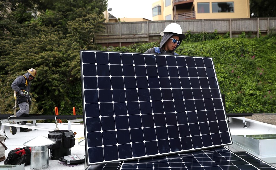 Luminalt solar installers Pam Quan (right) and Walter Morales (left) install solar panels on a roof in San Francisco on Wednesday. The California Energy Commission approved a regulation that would require all new homes in the state to have solar panels.