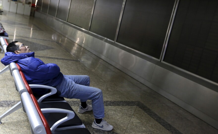 An investor rests in front of a dark electronic board at a Beijing brokerage house after China suspended trading Thursday for the second time this week.