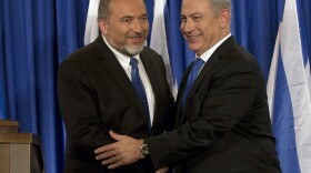 Israeli Prime Minister Benjamin Netanyahu (right) and Foreign Minister Avigdor Lieberman shake hands in front of the media after giving a statement in Jerusalem last month. Netanyahu said his Likud Party will join forces with the hard-line party of his foreign minister in upcoming parliamentary elections.