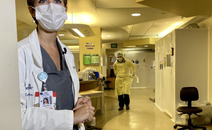 Danisha Jenkins, critical care services director at Sharp Chula Vista Medical Center, stands in the hospital's ICU unit while a team member dons a gown in the hallway, Aug. 21, 2020.