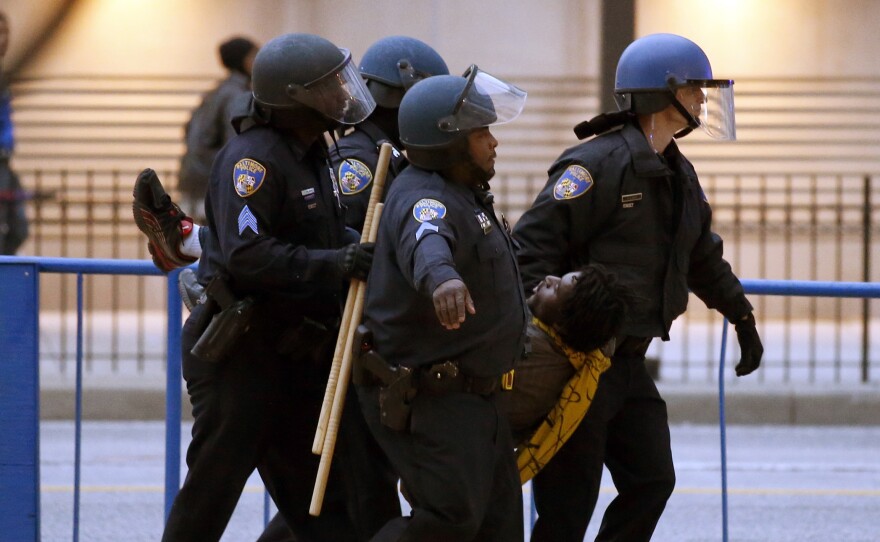 Police carry a detained man to a waiting police van after a march to City Hall for Freddie Gray, on Saturday. Authorities say 34 people were arrested in the protest over Gray, who died in police custody last week.