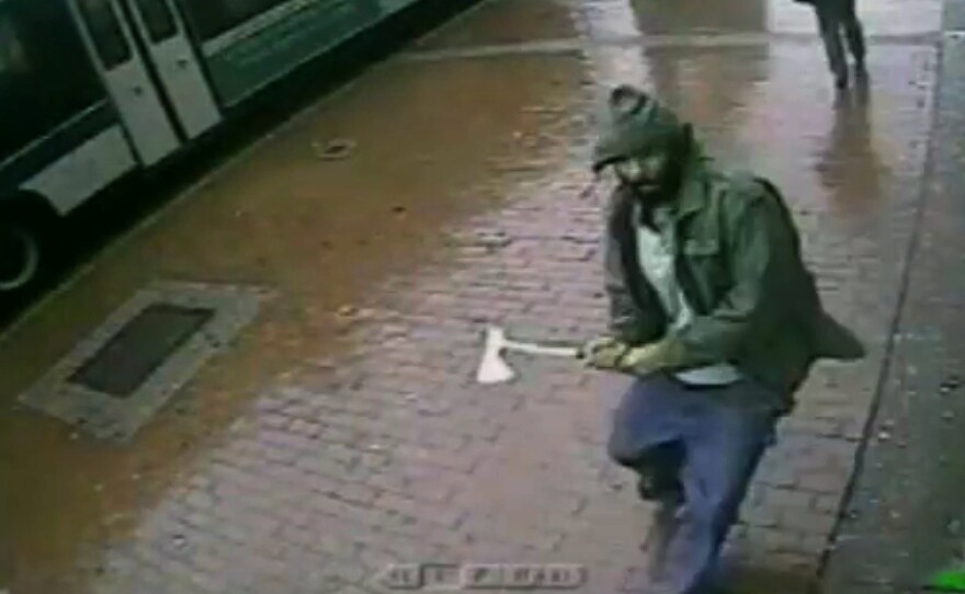 In this frame grab taken from video provided by the New York Police Department, an unidentified man approaches New York City police officers with a hatchet, on Thursday. The man was fatally shot by police after he wounded two officers.