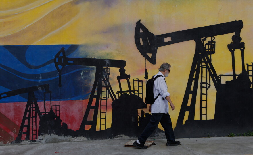 A pedestrian walks past a mural featuring oil wells in Caracas, Venezuela, Saturday, Aug 29, 2026, a day after President Donald Trump announced a deal giving the United States a stake in Venezuela's oil reserves.