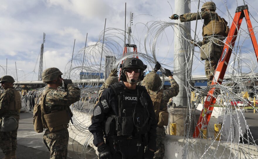 Troops set up concertina wire as a Customs and Border Protection agent stands guard on the U.S. side of the border with Mexico, on Thanksgiving Day.