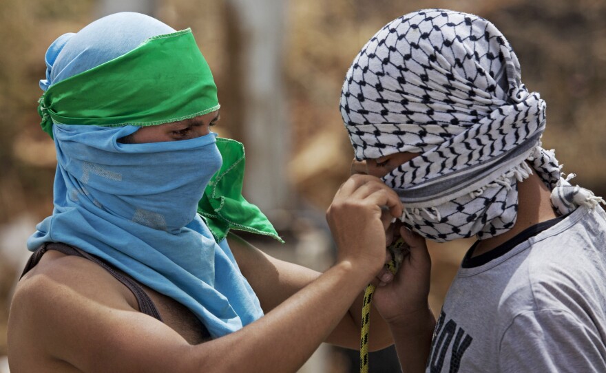 A Palestinian with a green headband, which identifies him as a Hamas supporters, helps a fellow protester with a black-and-white scarf, the symbol of the Fatah movement. They were both taking part in a demonstration near the West Bank city of Ramallah on June 4. The factions agreed to end their feud earlier this year, but many of their supporters remain bitter rivals.