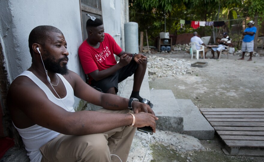Odne Laguerre (left) and evacuee Bobson Timothee pass the time while other evacuees play cards at the Laguerre home.
