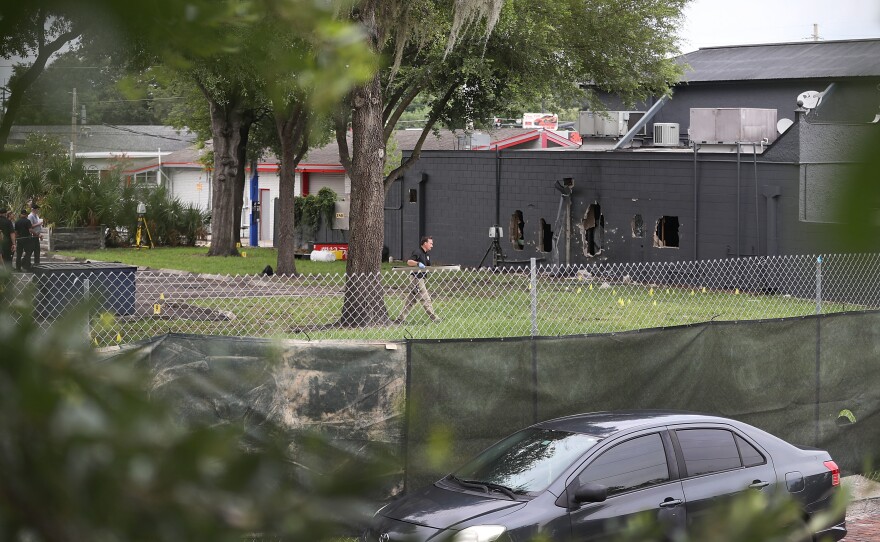 FBI agents investigate near the damaged rear wall of the Pulse club, where police used explosives and an armored vehicle to break through the cinder block.