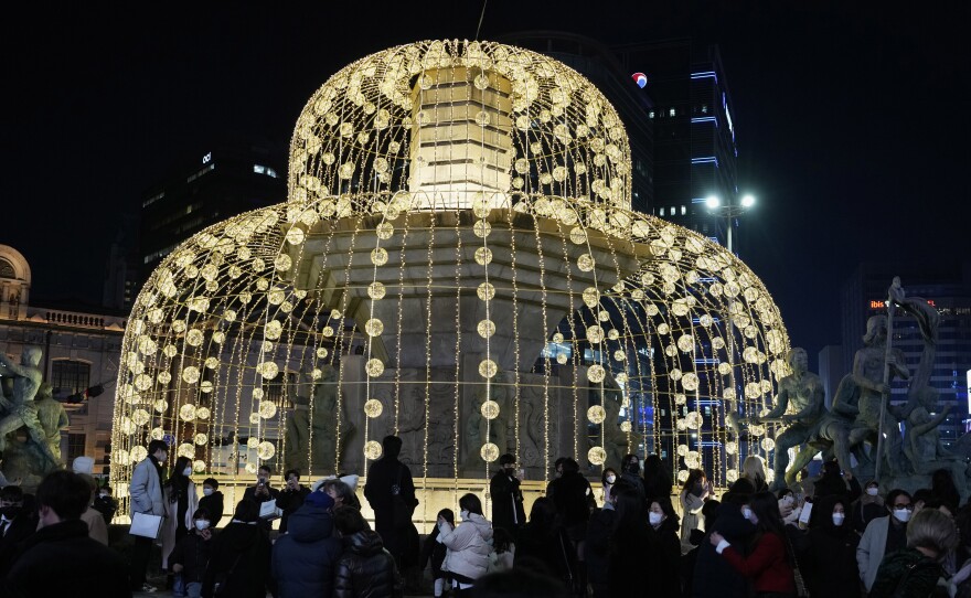 People gather around illuminated Christmas decorations on Christmas Eve in Seoul, South Korea.