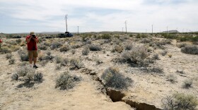 A visitor takes a photo of a crack on the ground following recent earthquakes outside of Ridgecrest, Calif. Sunday, July 7, 2019,
