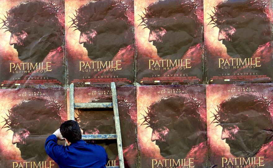 A worker adjusts posters promoting Mel Gibson's <em>The Passion of the Christ</em> in Bucharest, Romania, in April 2004. Worldwide, the film brought in more than $600 million in box-office earnings.