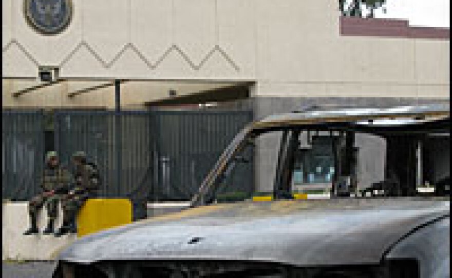 Two Yemeni soldiers sit outside the gates of the U.S. Embassy in San'a the morning after attackers in two vehicles loaded with explosives mounted a carefully planned attack on the compound.