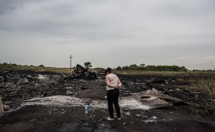 A woman looks at the wreckage in Grabovka. Parts of the crash site were still smoldering Friday.