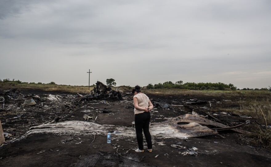 A woman looks at the wreckage in Grabovka. Parts of the crash site were still smoldering Friday. 