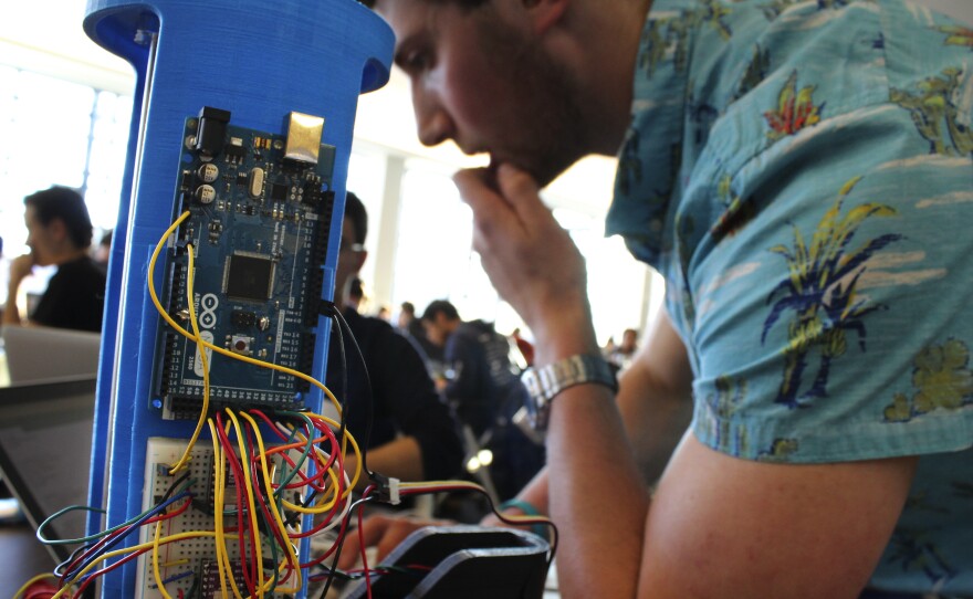 David Kaplan, a University of Maryland, College Park sophomore, tinkers with a robotic arm programmed to play tic-tac-toe at the Georgetown Hackathon in Washington, D.C.