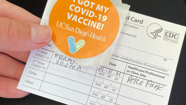 Community health worker Dalia Mohammad holds her immunization card and a COVID-19 vaccine sticker after receiving her first dose at the San Diego County vaccination super site at Petco Park, Jan. 11, 2021. 