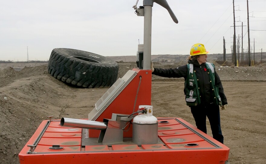 Ainslie Campbell, environmental sustainability manager for Shell's oil sands operation, demonstrates a device to keep migrating birds out of grimy water that collects at reclamation sites.