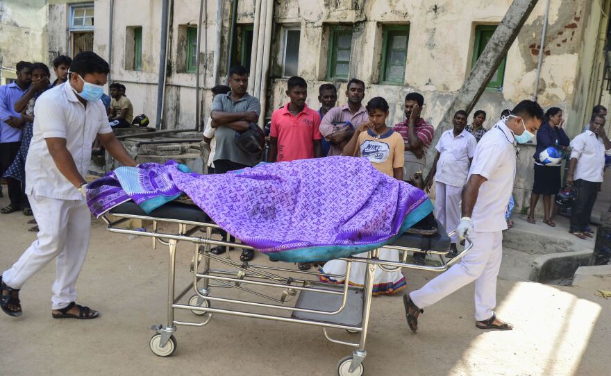 Hospital workers transport a body on a stretcher at a hospital morgue following the explosion at a church in Batticaloa.