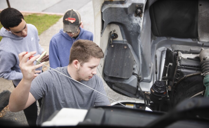 The students in the trucking class take their time going through the steps of a pre-trip inspection, checking out the truck from front to back and under the hood.