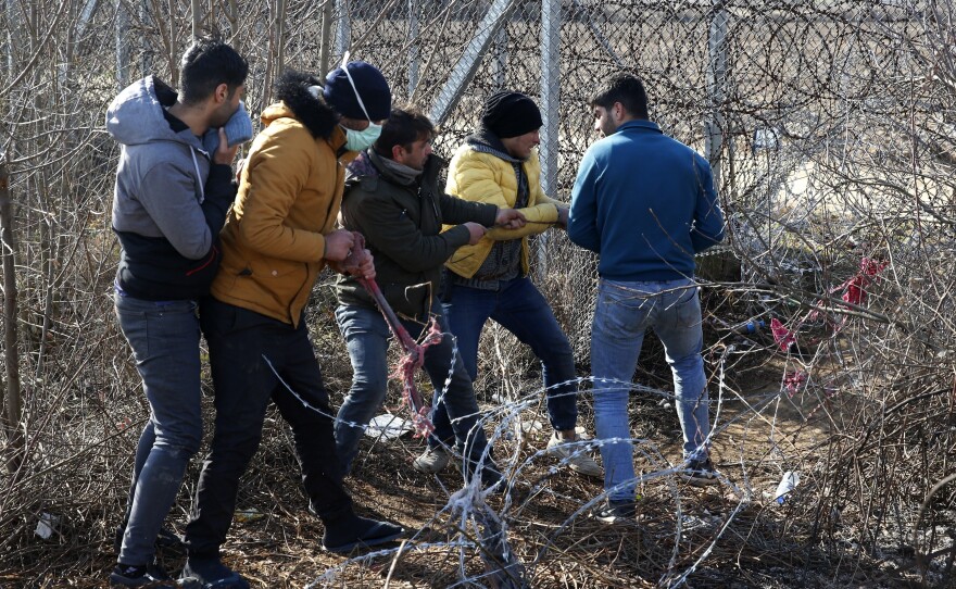 Migrants try to cut the fence at the Turkish-Greek border near the Pazarkule border gate in Edirne, Turkey, on Monday. Thousands of migrants and refugees massed at Turkey's western frontier, trying to enter Greece by land and sea after Turkey said its borders were open to those hoping to head to Europe.